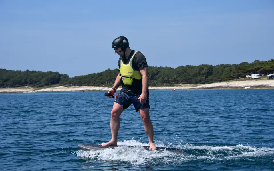 Élève debout sur un e-foil, casque et gilet