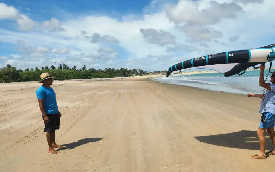 Plage avec une aile de wing foil portée à bout de bras