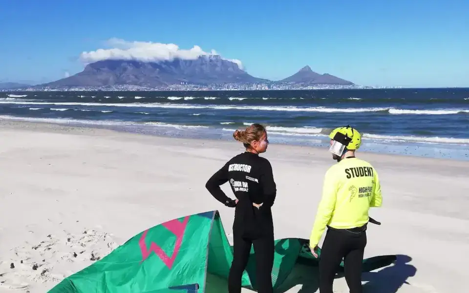 Deux personnes sur la plage avec une aile de kite posée au sol