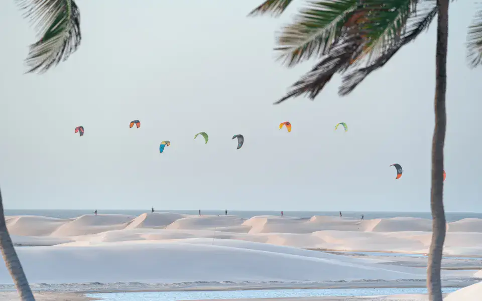 Kitesurfeurs sur un plan d'eau bordé de dunes et de palmiers