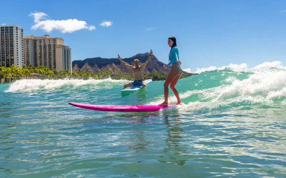 Élève debout sur une planche rose devant Diamond Head