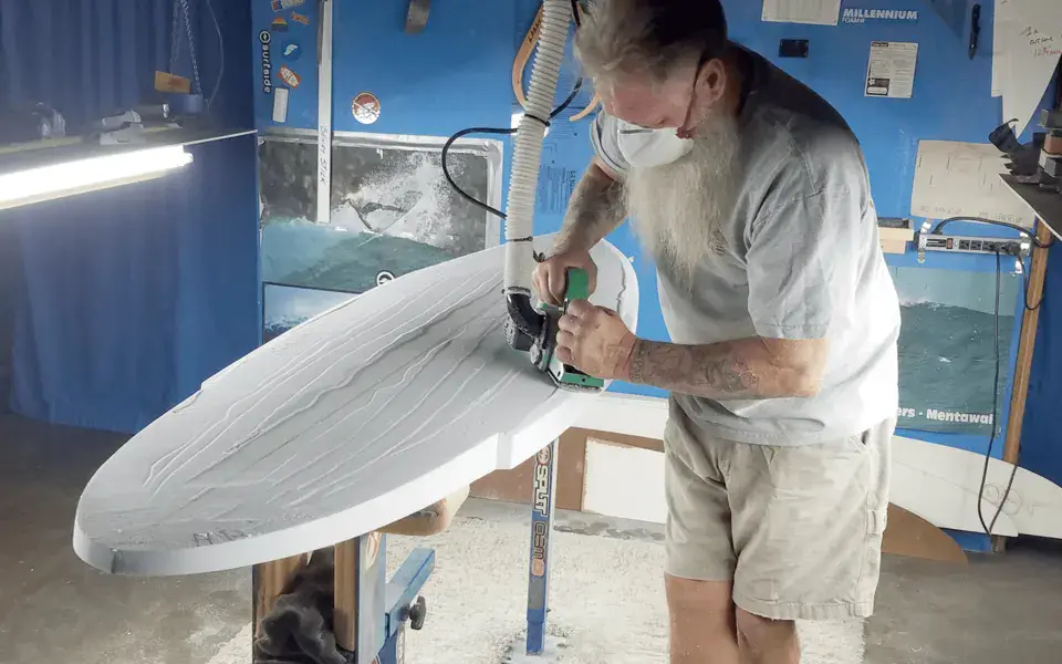 Le shapeur ponce une planche dans l'atelier