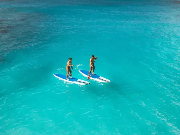 Deux personnes en stand up paddle sur une eau turquoise