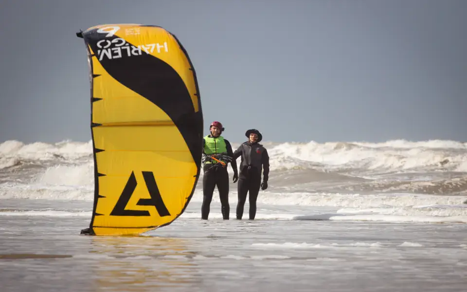 Deux personnes avec une grande kite jaune au bord de l'eau