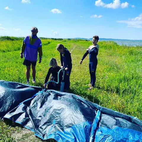 Montage d'un kite sur une prairie au bord de l'eau