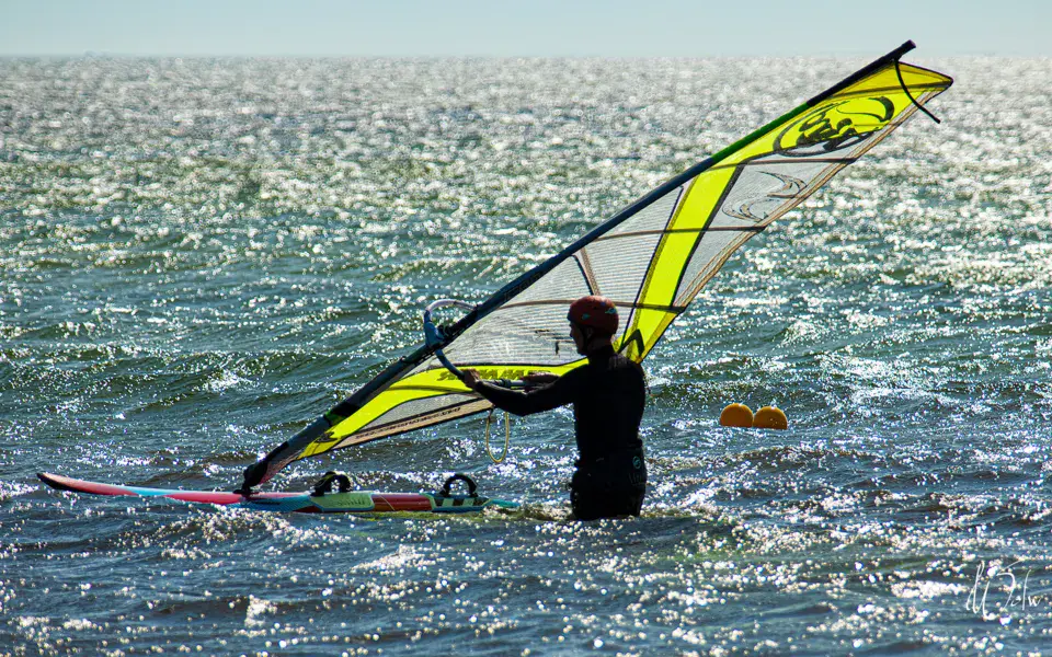 Véliplanchiste dans l'eau avec une voile jaune