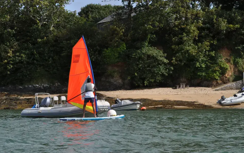 Windsurfeur à l'apprentissage sur l'eau, avec un bateau d'encadrement