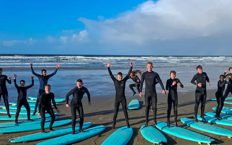 Groupe en combinaison alignés sur la plage avec leurs planches