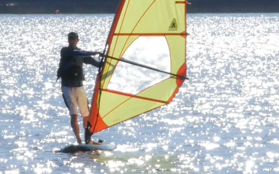 Un véliplanchiste sous voile jaune sur le lac