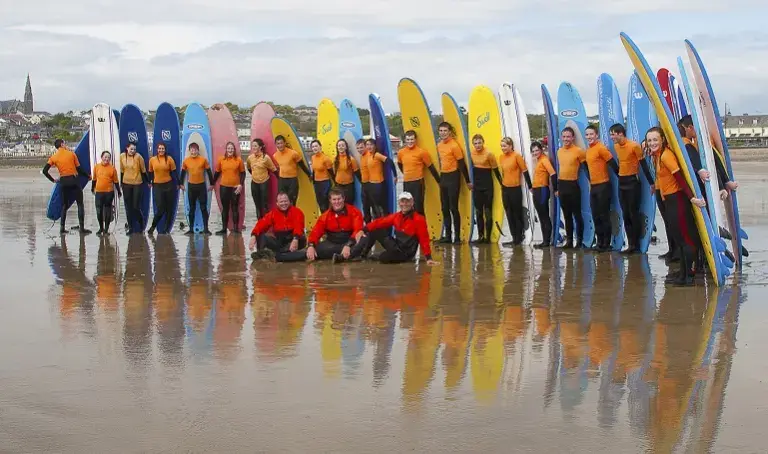 Groupe en combinaison alignés devant leurs planches sur la plage