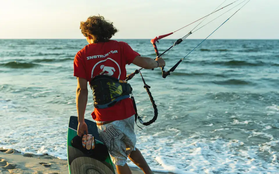 Kitesurfeur remontant de la plage avec sa planche