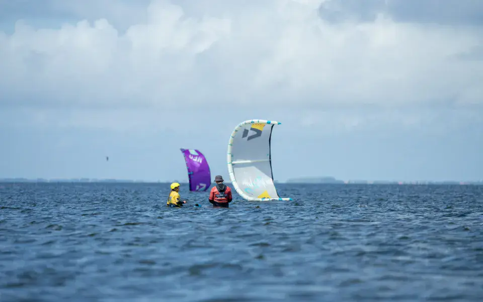 Cours de kitesurf sur l'eau calme du fjord, avec deux ailes dans le ciel