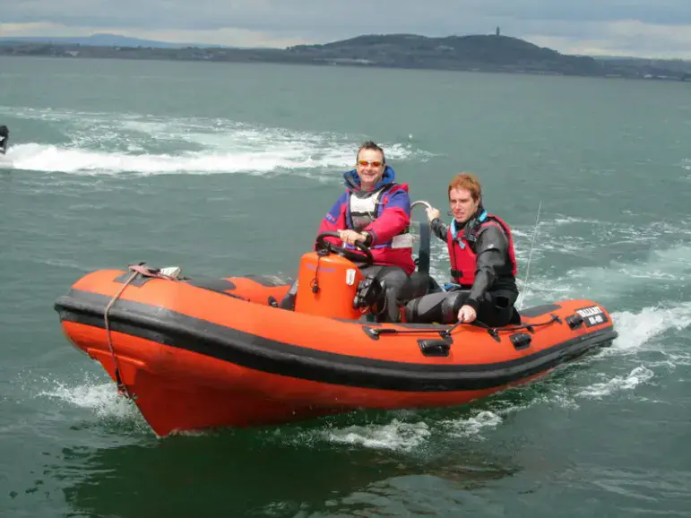 Bateau de sécurité pneumatique orange avec deux personnes à bord