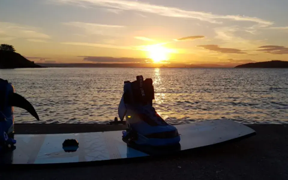 Planche de kite posée au bord de l'eau, au coucher du soleil