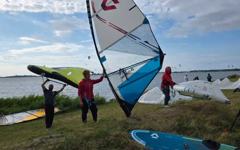 Voiles de windsurf tenues à la main au bord de l'eau