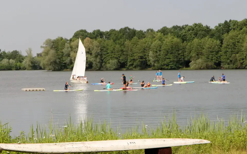Voilier et paddleurs sur le lac