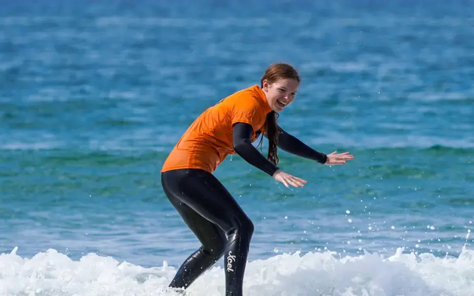 Élève debout sur sa planche dans les vagues