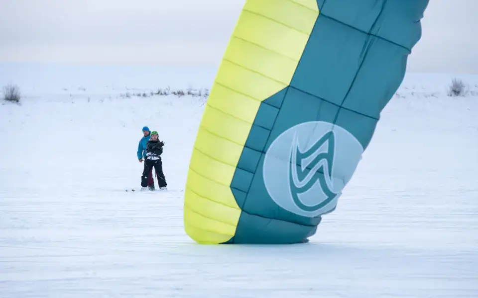 Une aile à caissons posée dans la neige pendant un cours de snowkite