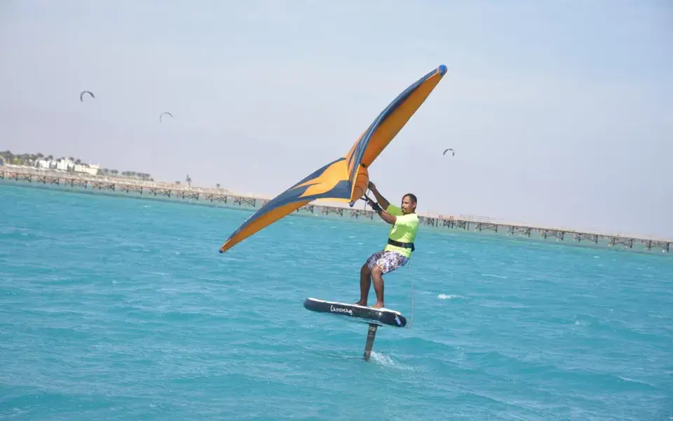 Un pratiquant de wing foil sur l'eau turquoise de la baie de Nabq