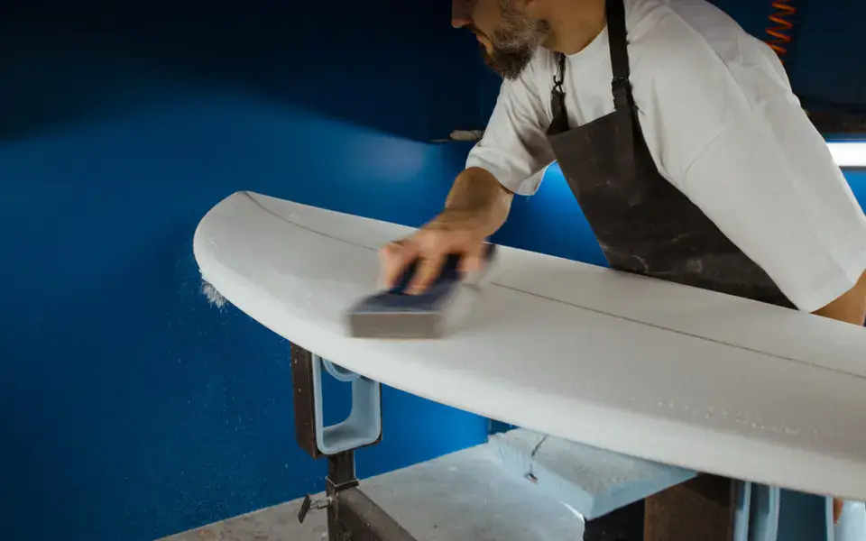 Ponçage d'une planche de surf dans l'atelier