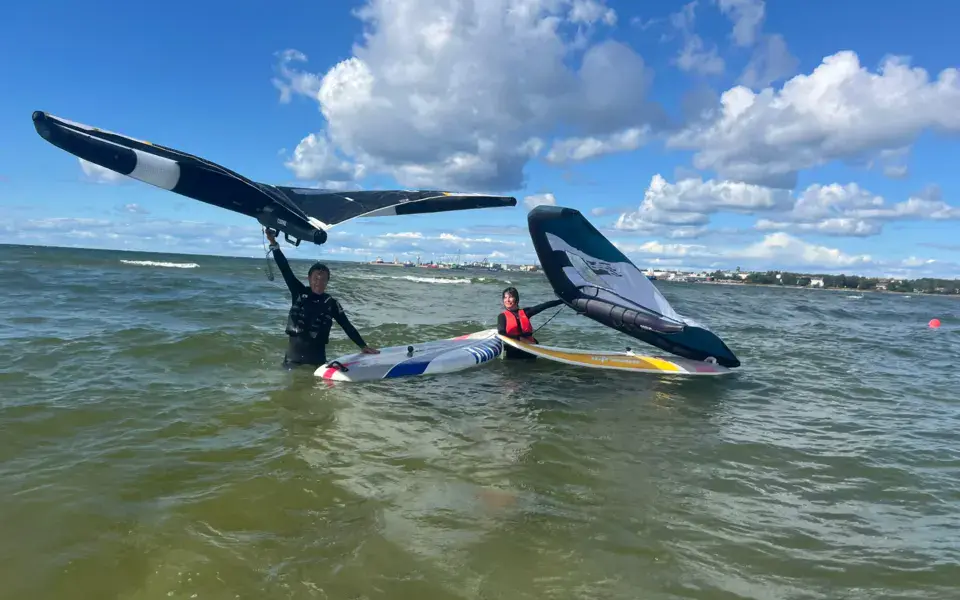 Deux pratiquants de wing foil dans l'eau avec leurs ailes et leurs planches