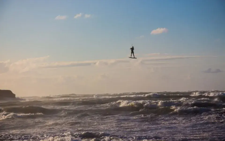 Kitesurfeur en plein saut au-dessus de vagues agitées