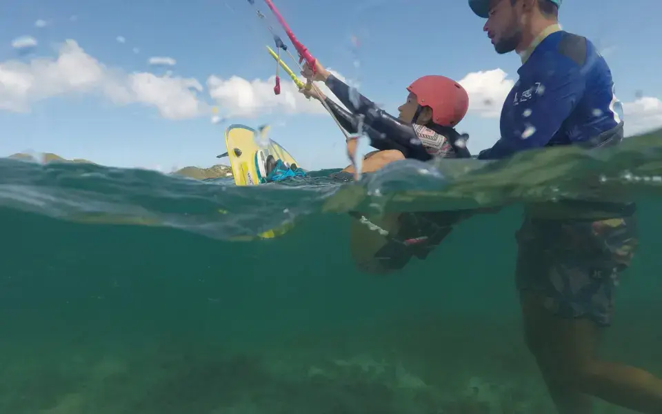 Moniteur de kitesurf avec un élève dans l'eau peu profonde