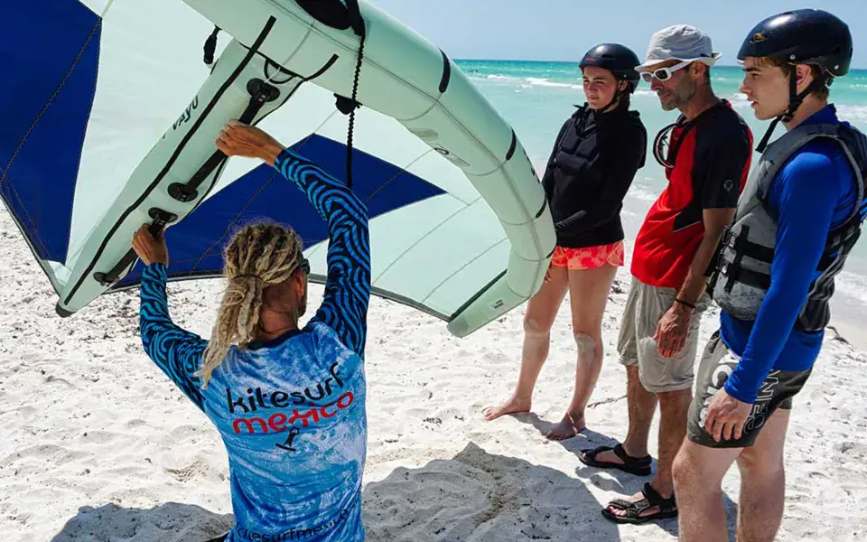 Moniteur de l'école avec un groupe d'élèves sur la plage avant un cours de wing foil