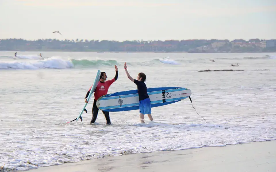 Deux surfeurs sortent de l'eau avec leurs planches sur la plage