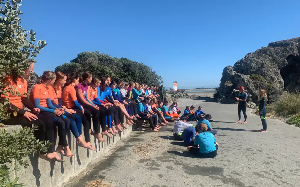 Groupe de surfeurs en combinaison réuni sur la plage avant un cours