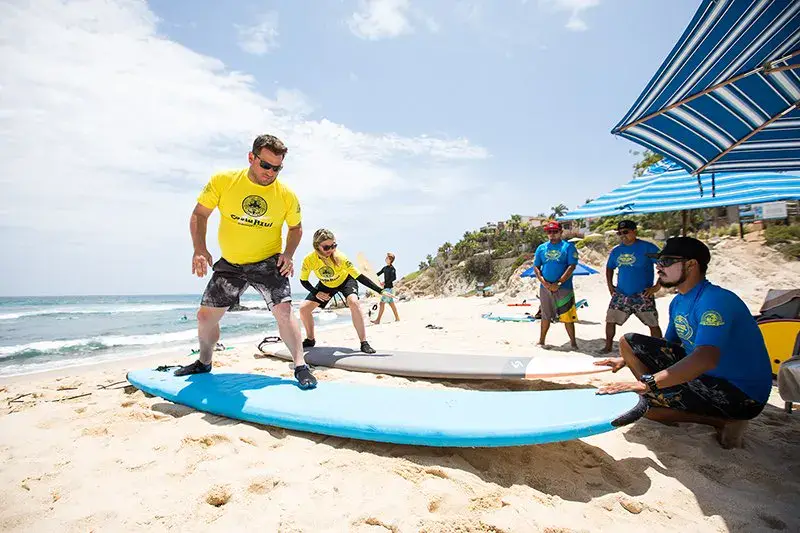 Moniteurs et élèves autour d'une planche sur la plage