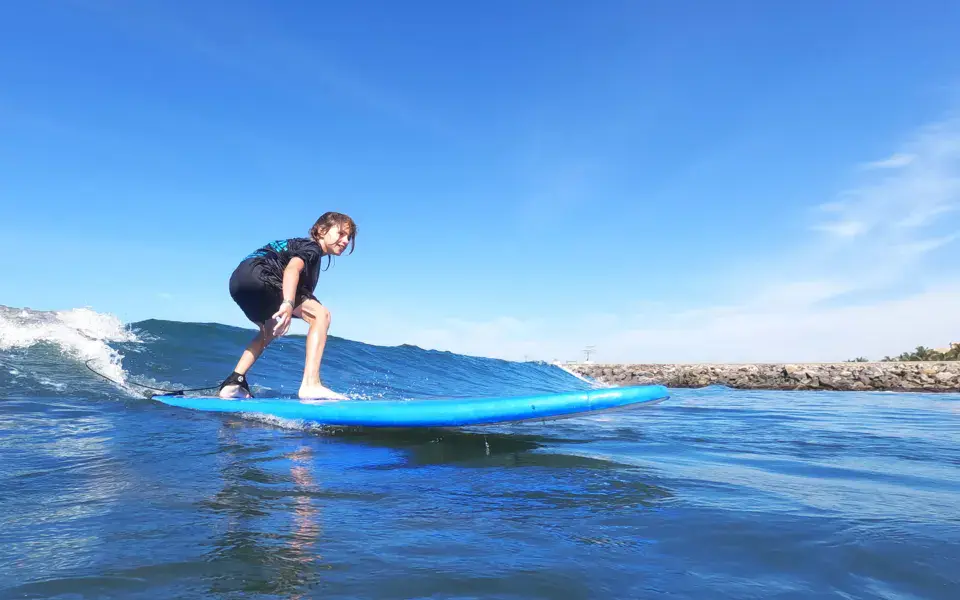 Un élève debout sur sa planche dans les vagues de la baie