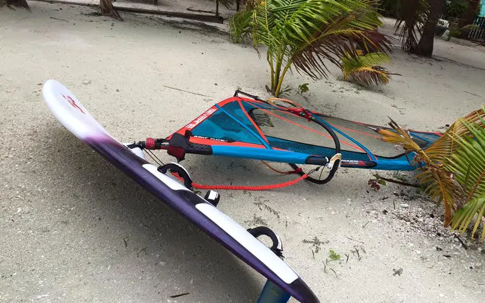 Planche à voile et gréement posés sur le sable