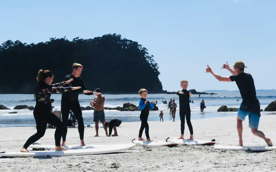 Moniteur et élèves à l'échauffement sur la plage, planches posées sur le sable