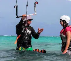 Moniteur et élève dans l'eau peu profonde avant un cours de kitesurf