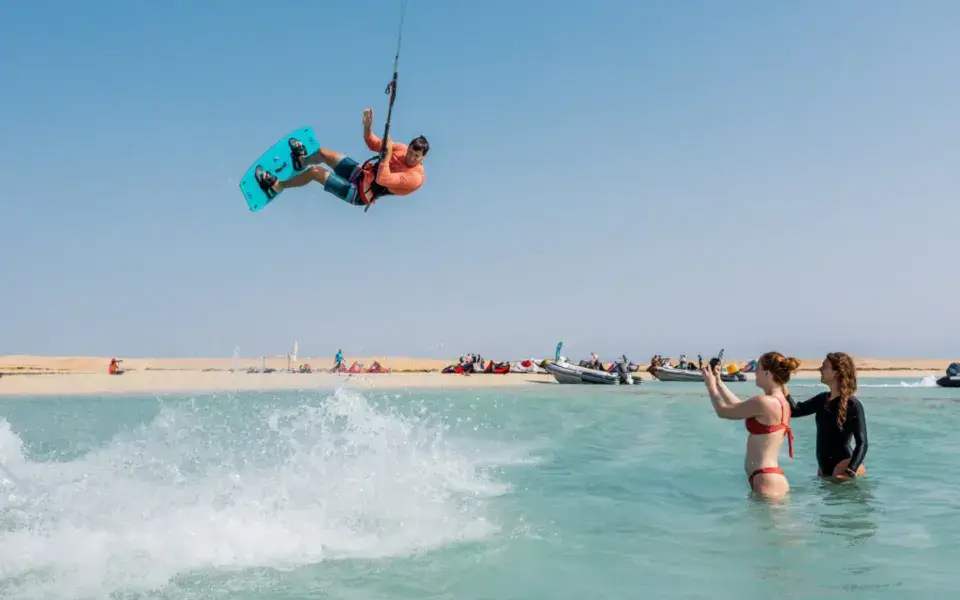 Kitesurfeur en saut près du banc de sable, élèves dans l'eau