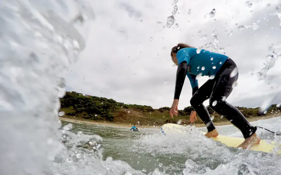 Une élève en cours de surf dans les vagues