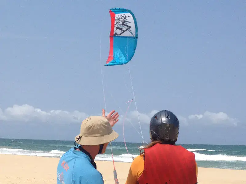 Moniteur et élève avec une aile de kitesurf lors d'un cours sur la plage