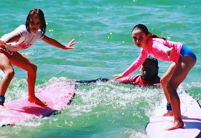 Deux élèves debout sur leurs planches dans les vagues