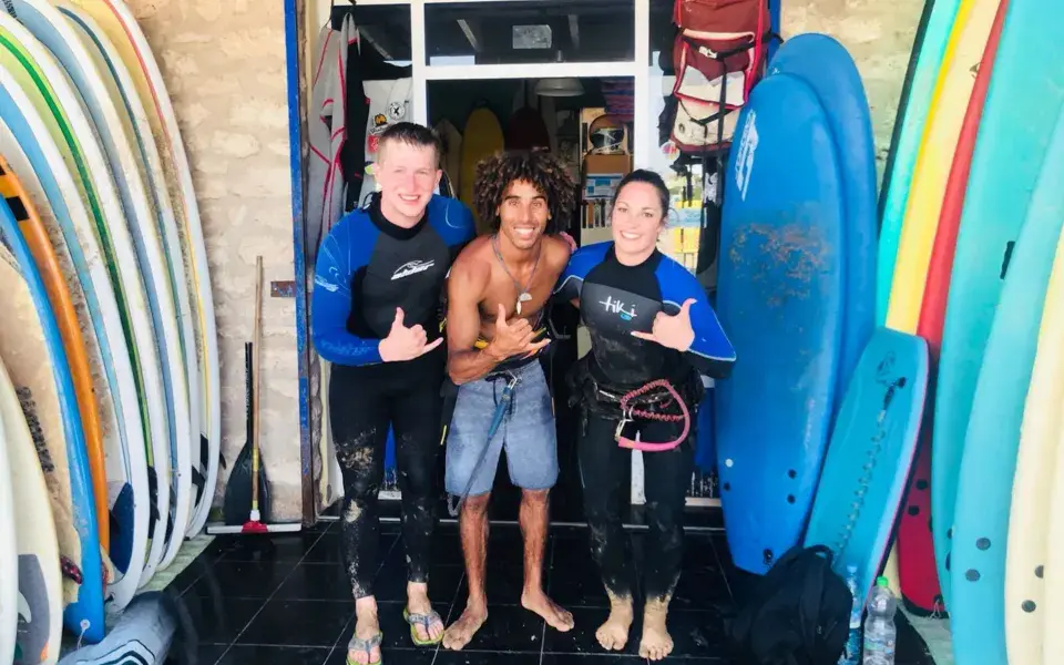 Élèves et moniteur devant le local de l'école, planches de surf alignées