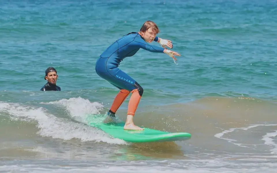 Élève debout sur sa planche lors d'un cours de surf
