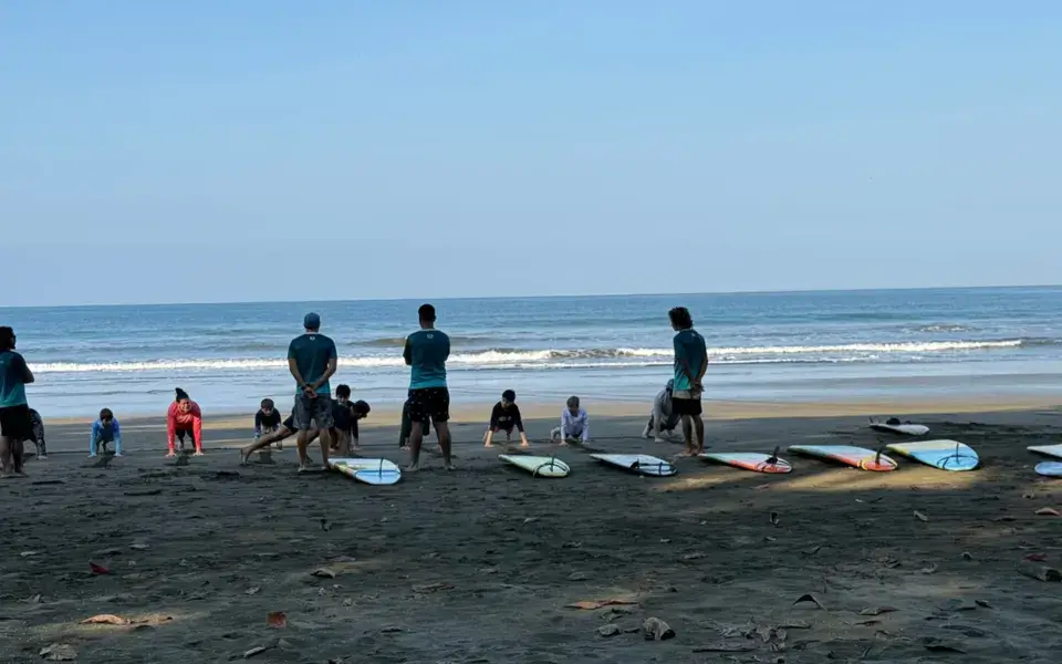 Groupe d'élèves avec leurs planches sur la plage, avant un cours