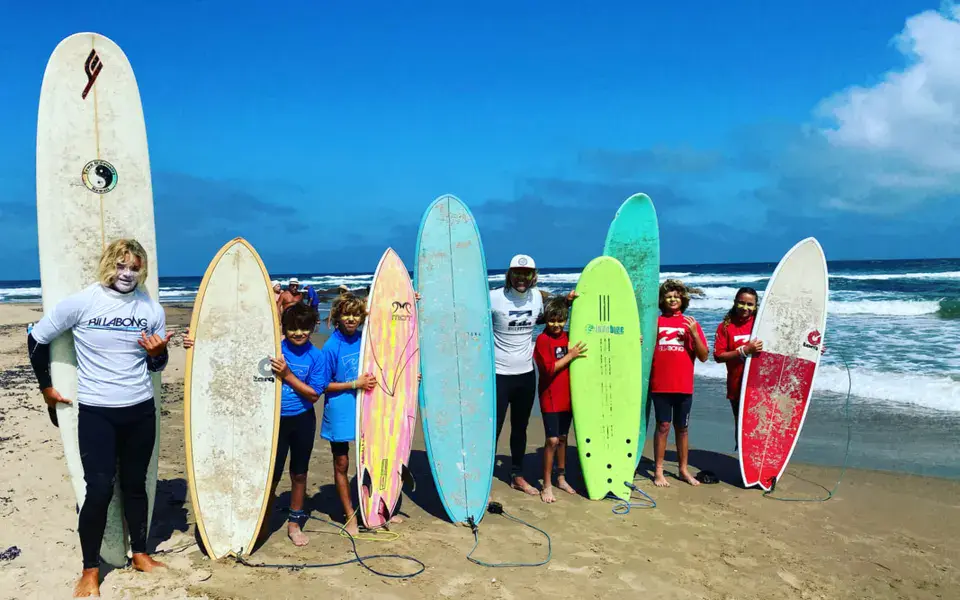Groupe d'élèves avec leurs planches de surf sur la plage