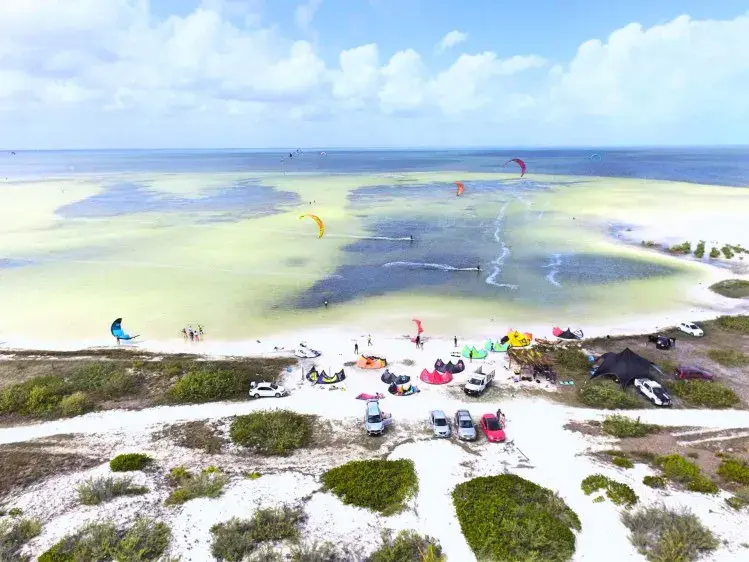 Vue aérienne d'une plage de sable blanc avec des kitesurfeurs sur l'eau