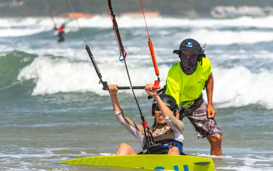 Un moniteur accompagne un élève dans l'eau pendant un cours de kitesurf