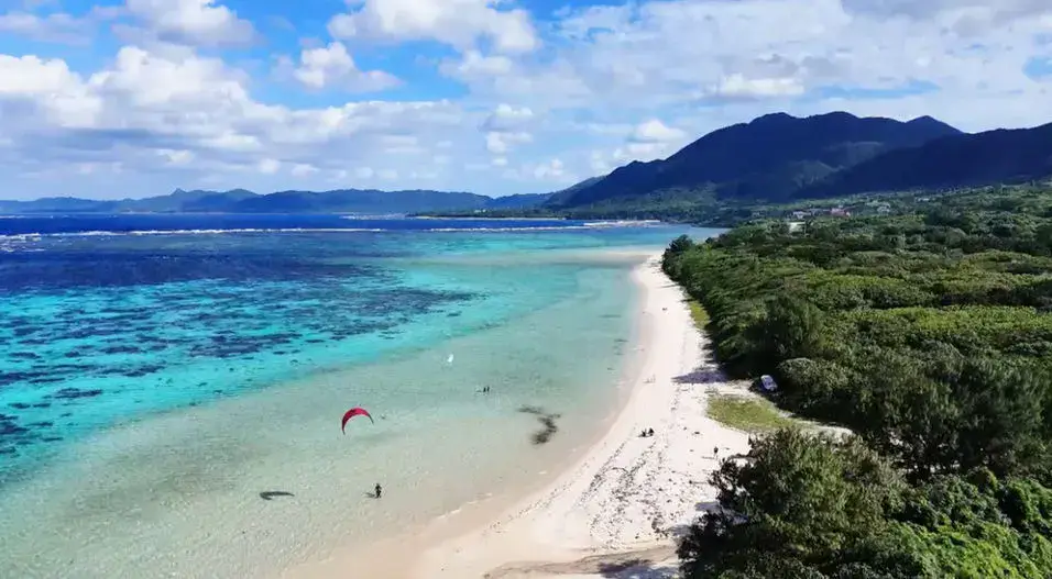 Plage de sable blanc et kitesurfeurs vus du ciel