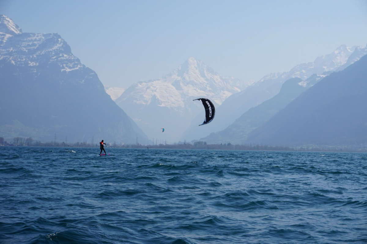 Kitesurf sur un lac alpin, au pied des sommets enneigés