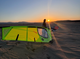 Gréement de windsurf posé sur la plage au coucher du soleil