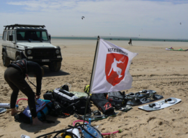 Matériel de kite et véhicule de l'école sur une plage, sous le drapeau Kiteswiss