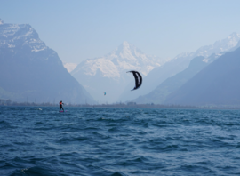 Kitesurf sur un lac alpin, au pied des sommets enneigés
